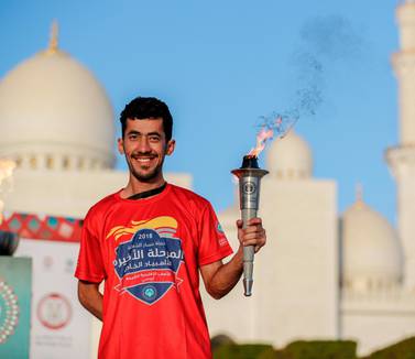A torch runner proudly holds up the torch infront of the Abu Dhabi Grand Mosque during a practice run last year. Victor Besa / The National
