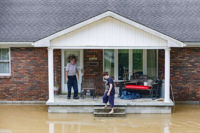 A couple stand on the porch of their flooded home. AFP