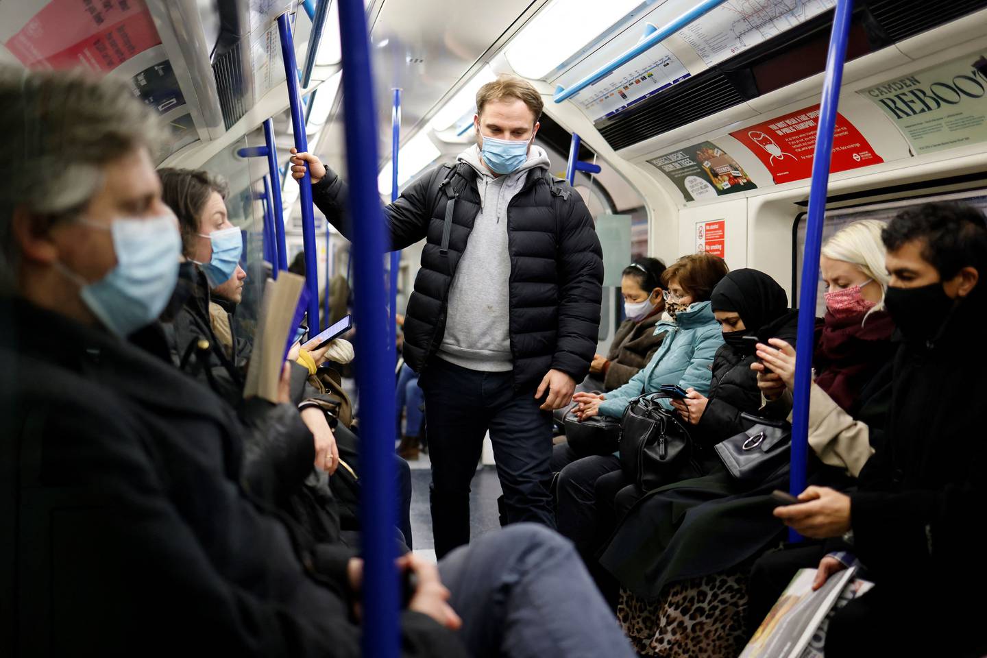 Commuters, most wearing face coverings to mitigate the spread of Covid-19, travel on a Transport for London (TfL) Victoria Line underground tube train carriage towards central London on January 5, 2022.  - British hospitals have switched to a "war footing" due to staff shortages caused by a wave of Omicron infections, the government said Tuesday, as the country's daily Covid caseload breached 200,000 for the first time.  (Photo by Tolga Akmen  /  AFP)