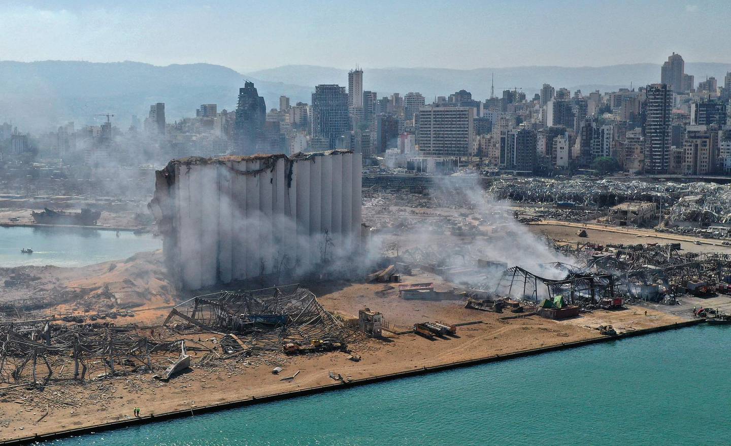 (FILES) A file photo taken on August 05, 2020 shows the massive damage done to Beirut port's grain silos (C) and the area around it on August 5, 2020, one day after a mega-blast tore through the harbour in the heart of the Lebanese capital with the force of an earthquake, killing more than 100 people and injuring over 4,000. France's foreign minister hit out at Lebanon's warring politicians on March 11, 2021, saying they were failing to help the country as it slid towards "total collapse". France has taken a leading role in trying to break the political deadlock in its former protectorate, with President Emmanuel Macron visiting the country twice last year. / AFP / -
