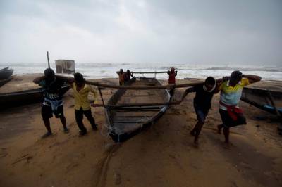 Men carry a fishing boat up a beach away from heavy waves brought by Cyclone Titli. AFP