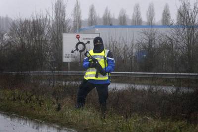A police officer stands along a road near the industrial area. Yoan Valat / EPA