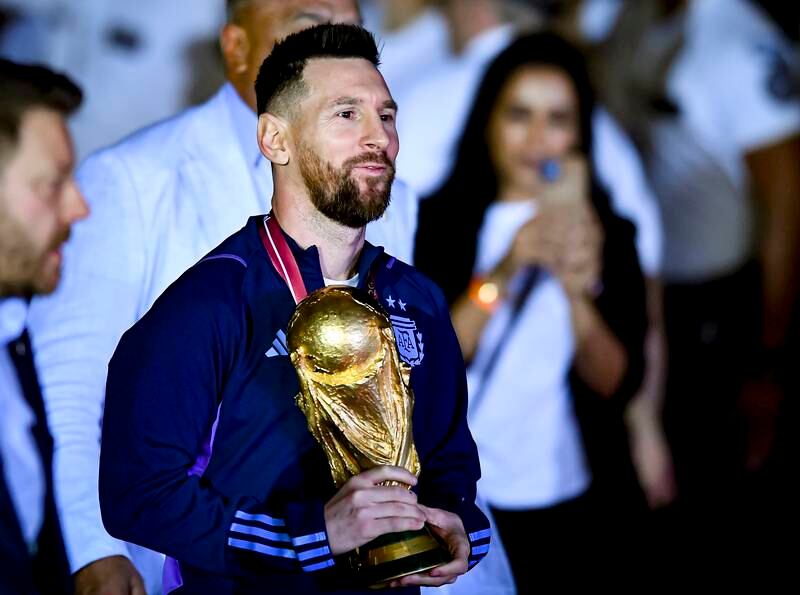 Lionel Messi with the World Cup trophy after arriving at Ezeiza International Airport. Getty