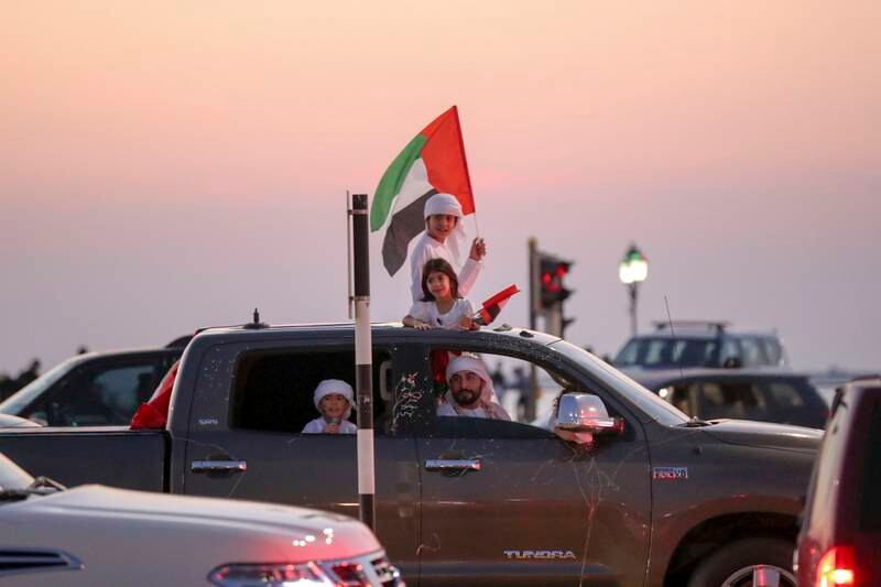 Proud Emirati children wave the UAE flag from a sunroof in Abu Dhabi.  Khushnum Bhandari/ The National