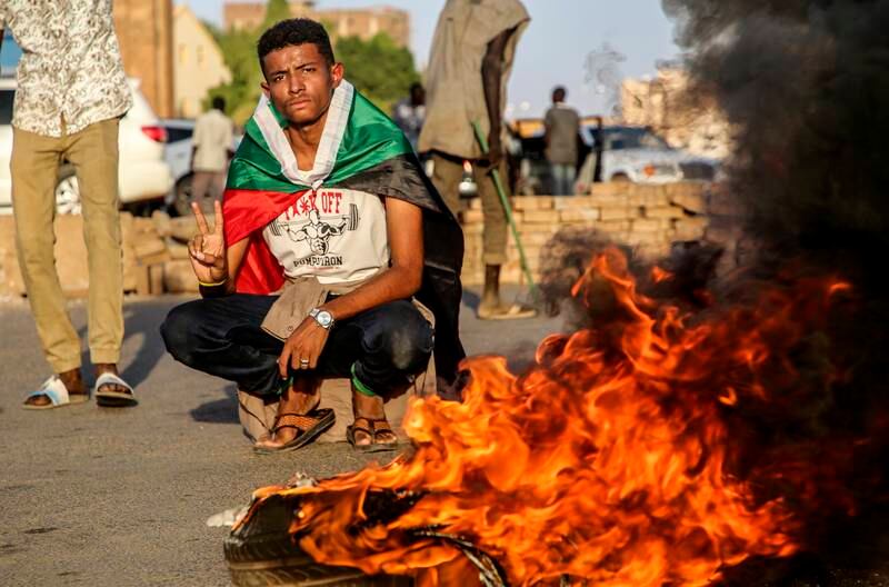 A Sudanese protester flashes a victory sign near a burning tyre as thousands of people joined anti-coup protests in Khartoum. EPA