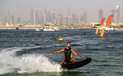 An athlete rides a jet-powered surfboard on the first day of the Dubai watersport festival, organised by the Dubai International Marine Club (DIMC), near the Burj Khalifa skyscraper in the Gulf emirate on June 25, 2020.  / AFP / KARIM SAHIB
