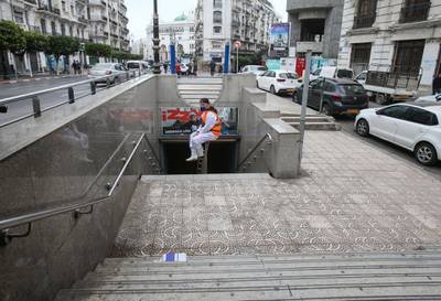 A cleaning worker wearing a protective suit sits in the entrance of metro station in Algiers, Algeria. Reuters