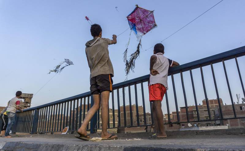 Egyptian youths fly handmade kites from an overpass on the capital Cairo's Ring Road in Egypt. AFP