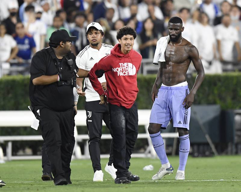 Weston McKennie and Antonio Rudiger check on a fan who was arrested for entering the pitch. Getty
