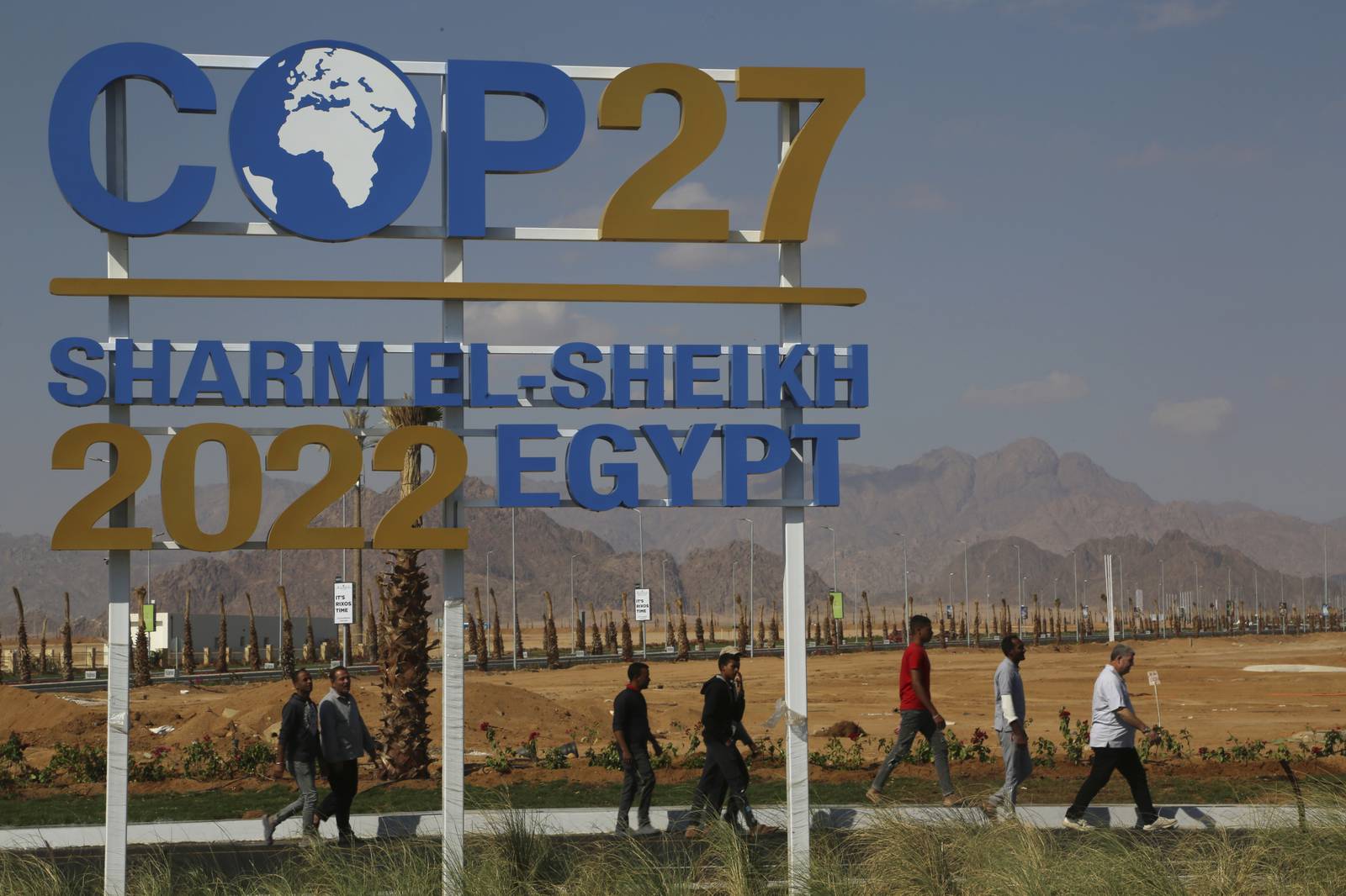 Workers walk past signage promoting this year’s United Nations global summit on climate change, known as COP27, adorns Peace Road, in Sharm el-Sheikh, South Sinai, Egypt. AP Photo