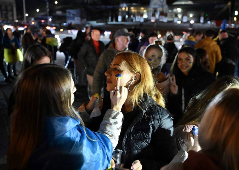 A woman gets colours of the Ukranian flag painted on her face as people gather in Maidan square to celebrate the liberation of Kherson, in Kyiv. AFP