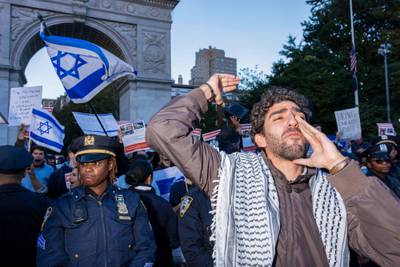 Pro-Israel counter protesters are kept away by police officers as people participate in a candlelight vigil organised by NYU students in support of Palestinians in Washington Square Park in New York. AFP