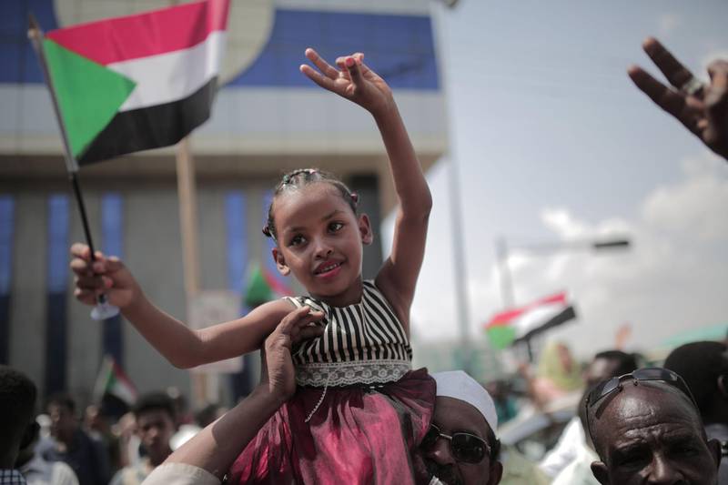 A young Sudanese girl waves a national flag as people celebrate outside the Friendship Hall in the capital Khartoum where generals and protest leaders signed a historic transitional constitution meant to pave the way for civilian rule in Sudan.  AFP