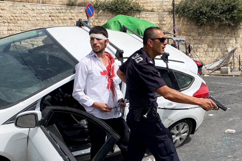 An Israeli police officer holds his weapon as he stands in front of an injured driver moments after witnesses said his car crashed into a Palestinian on a pavement during clashes near Lion's Gate, outside Jerusalem's Old City. Reuters