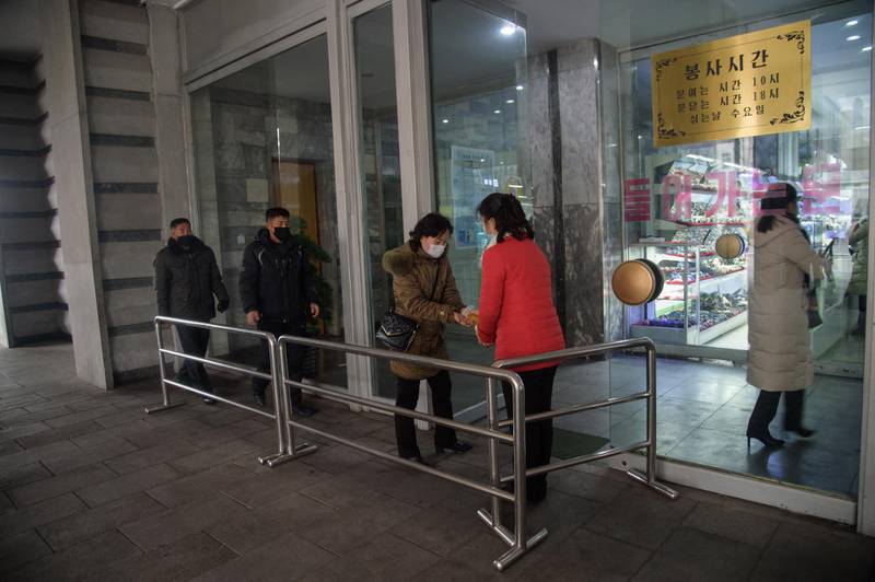 Shoppers receive hand sanitizer as they enter the Pyongyang Department Store No. 1, in Pyongyang on December 28, 2020. (Photo by KIM Won Jin / AFP)