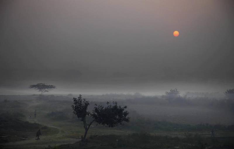 The sun rises over open land occupied by Indians living in shanties in New Delhi. Altaf Qadri / AP Photo