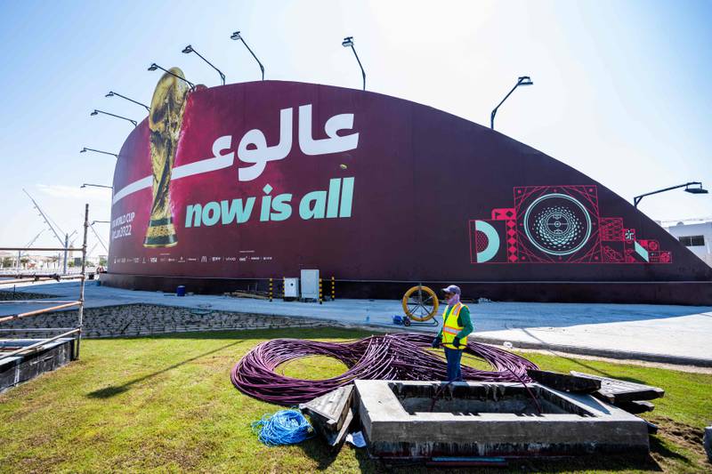 A man works in front of a billboard of the Qatar 2022 FIFA World Cup football tournament in Doha. AFP