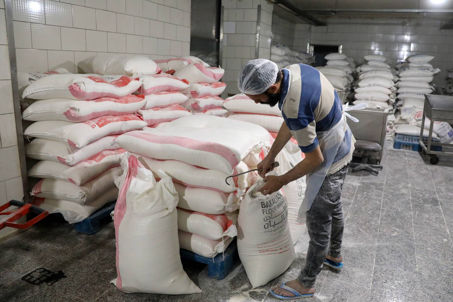 A worker opens a sack of flour to prepare bread dough at a bakery in Beirut on Tuesday. Bloomberg