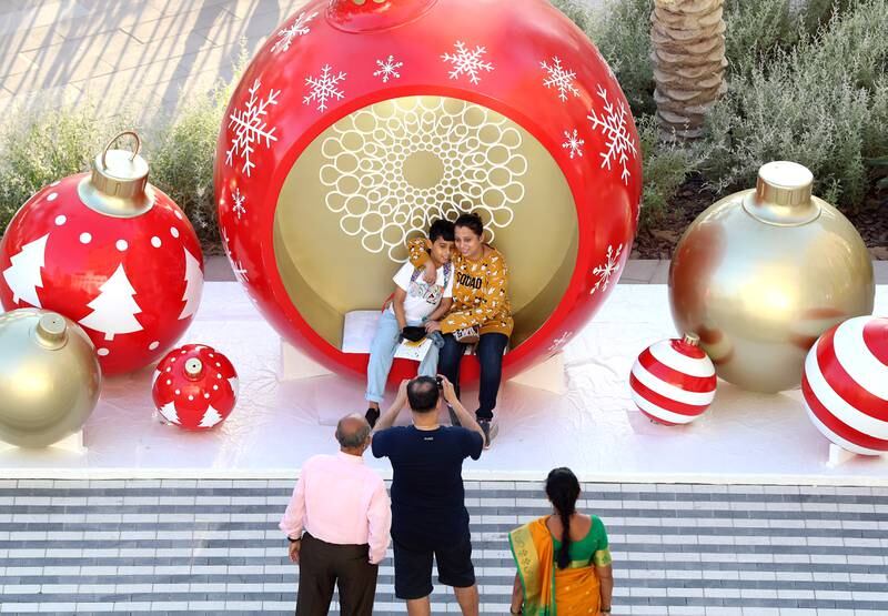 A family takes pictures in giant Christmas decorations at Expo 2020 in Dubai. Chris Whiteoak/ The National