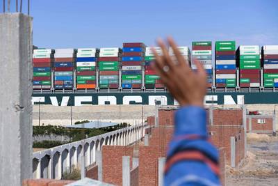 A man waves at the Panama-flagged MV 'Ever Given' container ship as it is tugged in Egypt's Suez Canal after it was fully dislodged from the banks, near Suez city. AFP