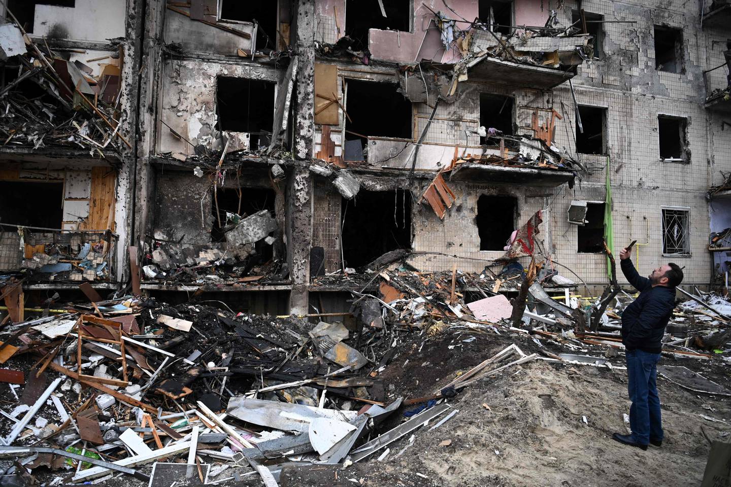 A man takes pictures of a damaged residential building in Kiev, where a military shell allegedly hit, on Thursday. AFP