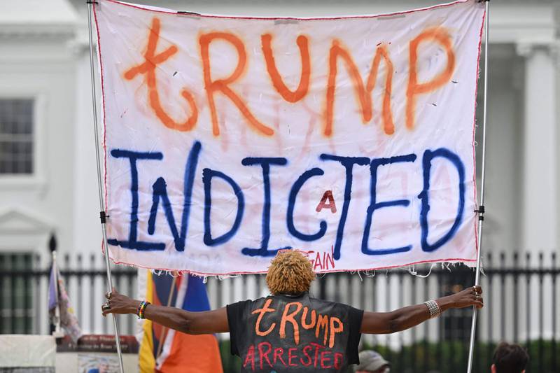 A woman celebrating the indictment holds a banner in front of the White House on Friday. AFP