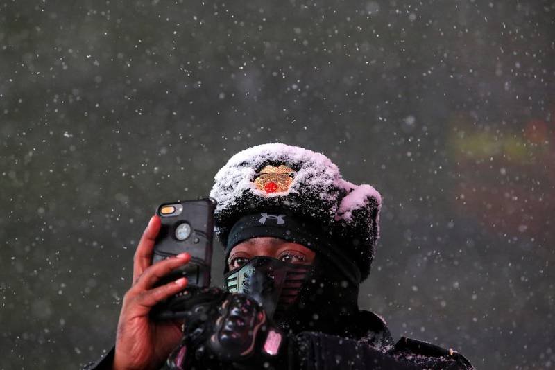 Baldwin Davis, a Times Square public safety sergeant, captures falling snow with his cellular device in Manhattan, New York City. Andrew Kelly / Reuters