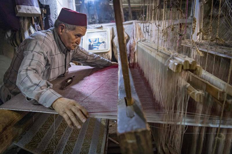 Ouazzani works on a tapestry at his workshop. AFP
