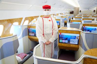 An Emirates cabin crew staff member demonstrates new health and safety measures introduced after the onset of the Covid-19 pandemic. Photo: Emirates