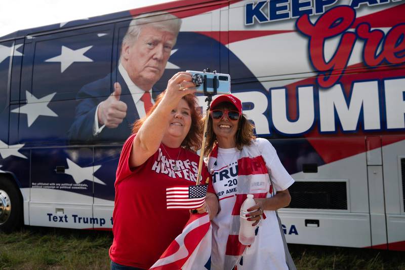MACON, GA - OCTOBER 16: Two women take a selfie next to a Trump bus in the parking lot of a campaign rally for President Donald Trump on October 16, 2020 in Macon, Georgia. President Trump continues to campaign against Democratic presidential nominee Joe Biden with 18 days until election day.   Elijah Nouvelage/Getty Images/AFP
== FOR NEWSPAPERS, INTERNET, TELCOS & TELEVISION USE ONLY ==

