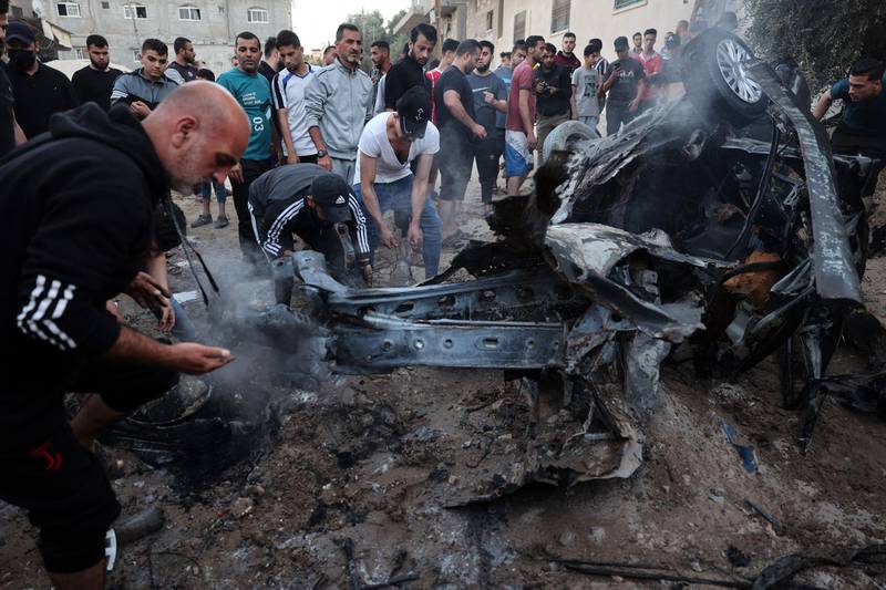 Palestinians gather around a car that burned after being hit by an Israeli missile in Gaza City. AFP