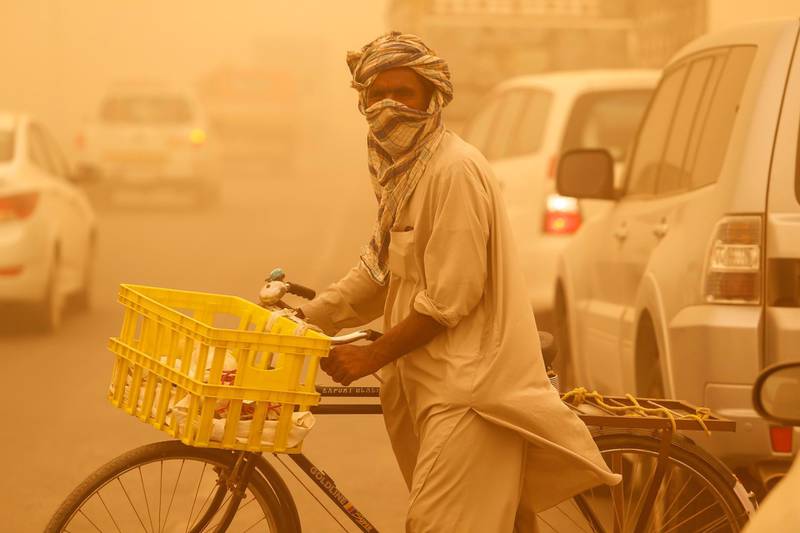 DUBAI, UNITED ARAB EMIRATES, 2 APRIL, 2015. A Pakistani nationalcovers his face with a head scarf while crossing the street as a sand storm rages in Dubai. (Photo: Antonie Robertson) Journalist: Standalone. Section: Arts & Life. *** Local Caption ***  AR_0204_Sandstorm-07.JPG