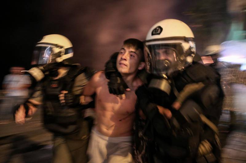 A protester is detained by riot policemen during clashes at the northern Greek city of Thessaloniki, Saturday, Sept. 8, 2018. Police in northern Greece have clashed with protesters outside an international trade fair where prime minister Tsipras made a keynote speech. (AP Photo/Dimitris Tosidis)