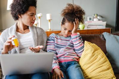 Portrait of an African American woman and her daughter at home, a mother is searching for information about medicine online