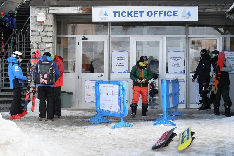 People prepare their skis and snowboards outside a closed ticket office in Ponte di Legno, Italy. Reuters