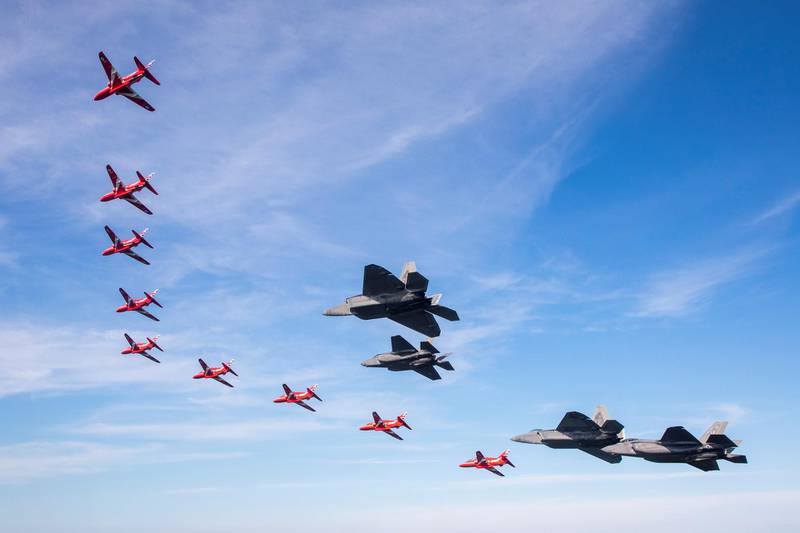US Air Force F-35s and F-22 Raptors in formation with the Red Arrows.