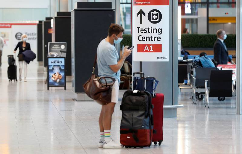 A passenger stands next to a Covid-19 testing centre sign in the international arrivals area of Terminal 5 in London's Heathrow Airport. Reuters