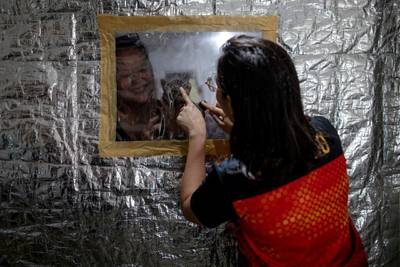 Jan Claire Dorado, 30, a doctor assigned to the coronavirus disease Emergency Room of East Avenue Medical Centre, bonds with her mother and cat from behind the small plastic window on her makeshift isolation room to protect her family from potential exposure to the coronavirus disease, in Quezon City, Metro Manila, Philippines. Reuters