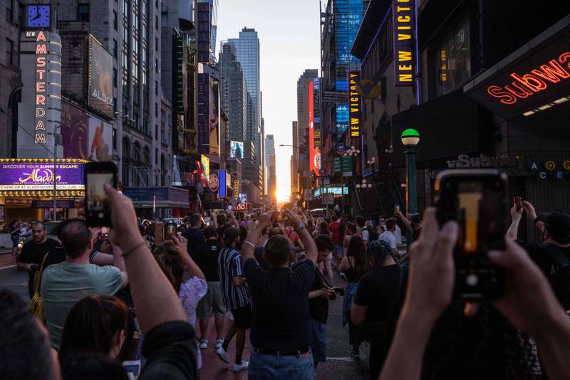 People gather to take pictures of Manhattanhenge in Times Square. AFP