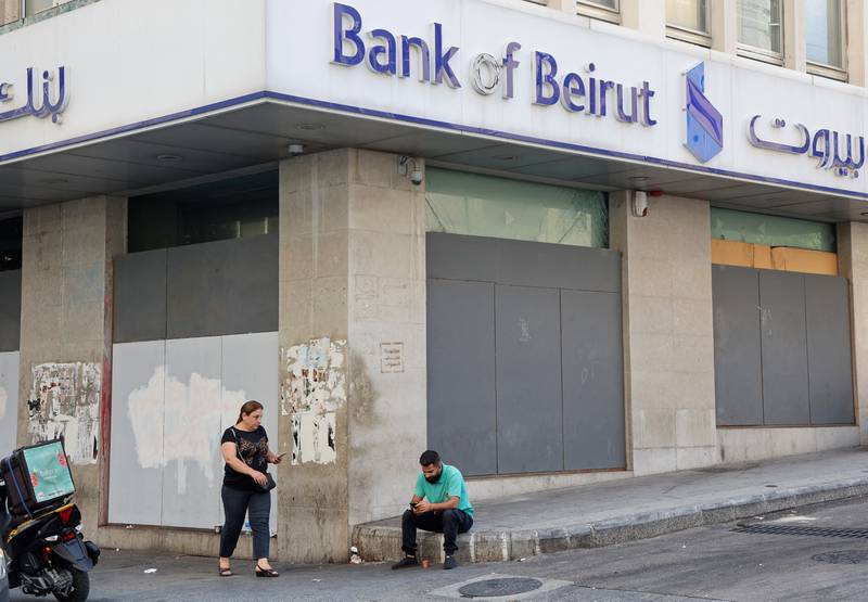 A man sits by a closed Bank of Beirut branch on Tuesday. Reuters