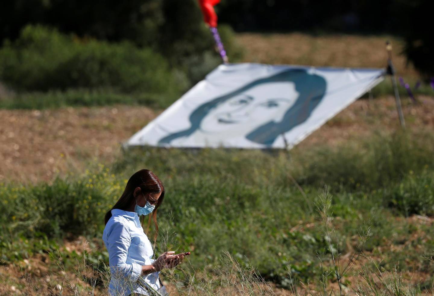 FILE PHOTO: A woman walks past a banner depicting anti-corruption journalist Daphne Caruana Galizia during a commemoration at the site where the journalist was assassinated with a car bomb in 2017, in Bidnija, Malta, October 16, 2020. REUTERS/Darrin Zammit Lupi/File Photo