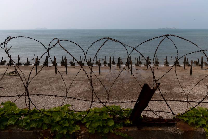 Metal spikes, known as dragon's teeth, and razor wire fortifications on a beach on Yeonpyeong Island, South Korea, with islands belonging to North Korea in the distance, June 26, 2020. On the sleepy island the threat of conflict is constant with North Korean coastal howitzers just 11 kilometres away. Bloomberg