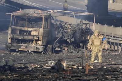 A Ukrainian soldier walks past the shell of a burnt military vehicle, on a street in Kiev. AP