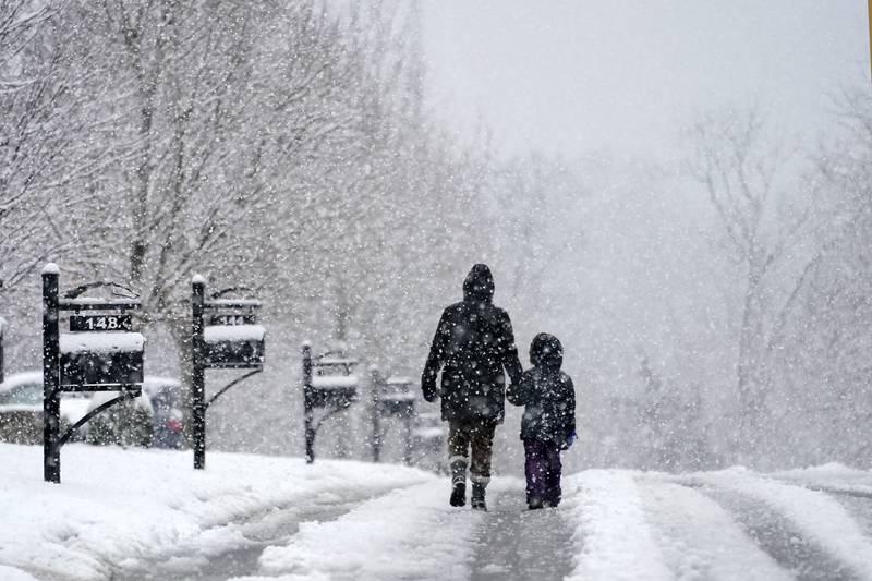 People go for a walk as snow falls Sunday, January 16, 2022, in Nolensville, Tennessee. AP Photo