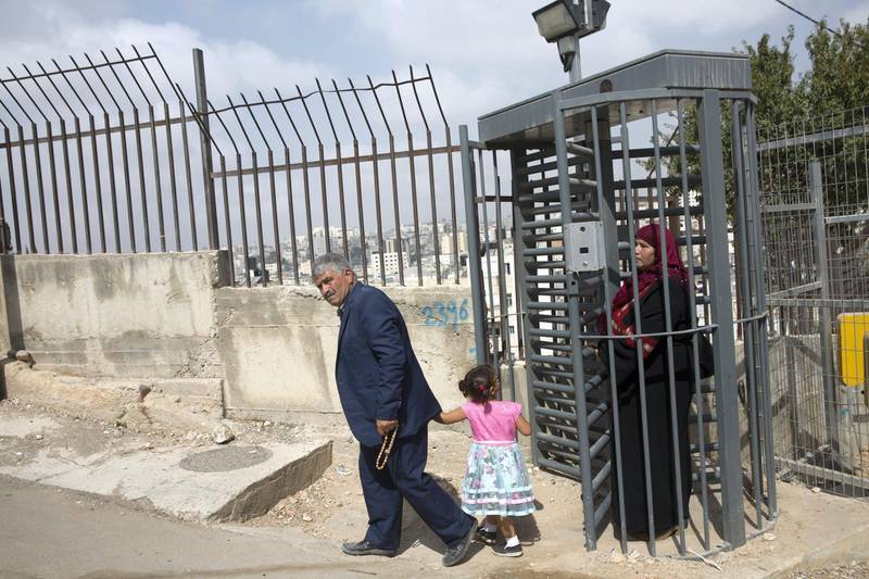 A Palestinian family crosses an Israeli checkpoint in the Palestinian Tel Rumeida neighborhood, which, along with three other Hebron enclaves houses 800 illegal settlers who live among its 200,000 Palestinians.Hebron . The Israeli government opened an archeological park nearby . (Photo by Heidi Levine for The National).