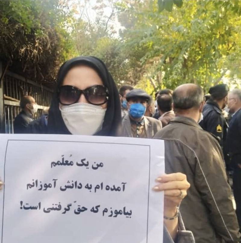 A teacher in Iran holds up a sign that reads: "I am a teacher, I have come to teach my students that rights are worth fighting for."