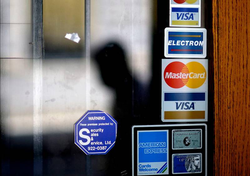 FILE - In this July 18, 2012, file photo, a pedestrian walks past credit card logos posted on a downtown storefront in Atlanta. On Monday, Sept. 11, 2017, Equifax said it has made changes to address customer complaints since it disclosed a week earlier that it exposed vital data on about 143 million Americans. Equifax has come under fire from members of Congress, state attorneys general, and people who are getting conflicting answers about whether their information was stolen. Equifax is trying again to clarify language about people��������s right to sue, and said Monday it has made changes to address customer complaints. (AP Photo/David Goldman, File)
