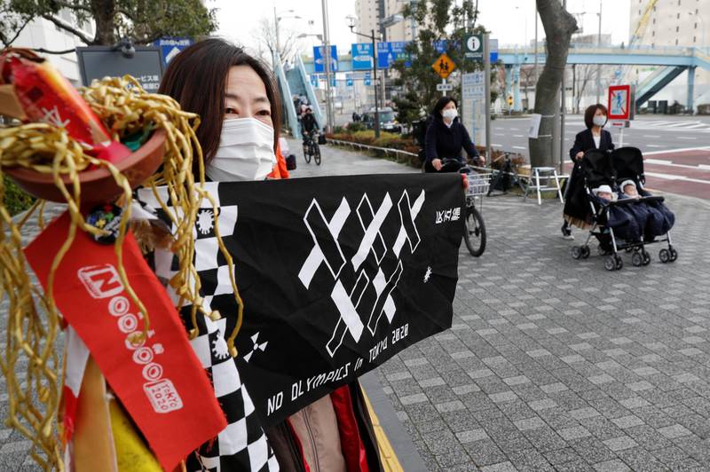 Women pass a protester joining a rally in front of a building housing the Organising Committee of the 2020 Tokyo Olympic Games to demand the Games' cancellation and to denounce comments made by Tokyo 2020 Olympics chief Yoshiro Mori in Tokyo, Japan, February 12, 2021. REUTERS/Kim Kyung-Hoon