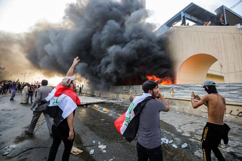 Protesters gather next to a burning building amid clashes with Iraqi riot police between the capital Baghdad's Tahrir Square and the high-security Green Zone district. AFP