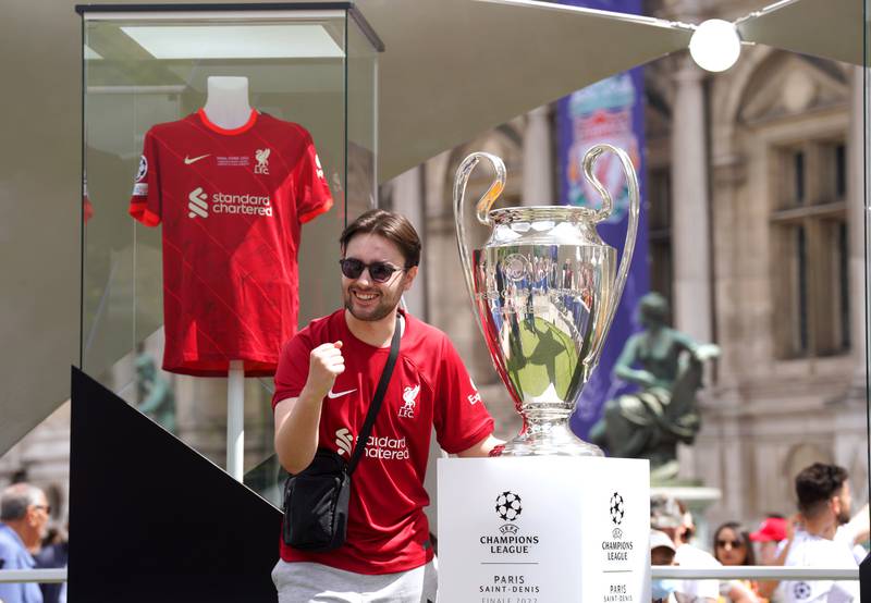 A Liverpool fan poses with the Champions League trophy at the Trophy Experience held at the Hotel de Ville. PA